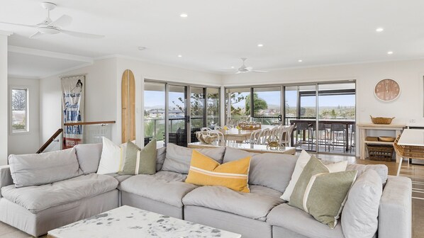 A modern living room with a sectional sofa, a coffee table, and a dining area with a view.