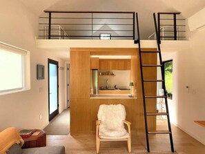 Um loft moderno com cozinha, uma cadeira de madeira e uma escada para o andar superior.