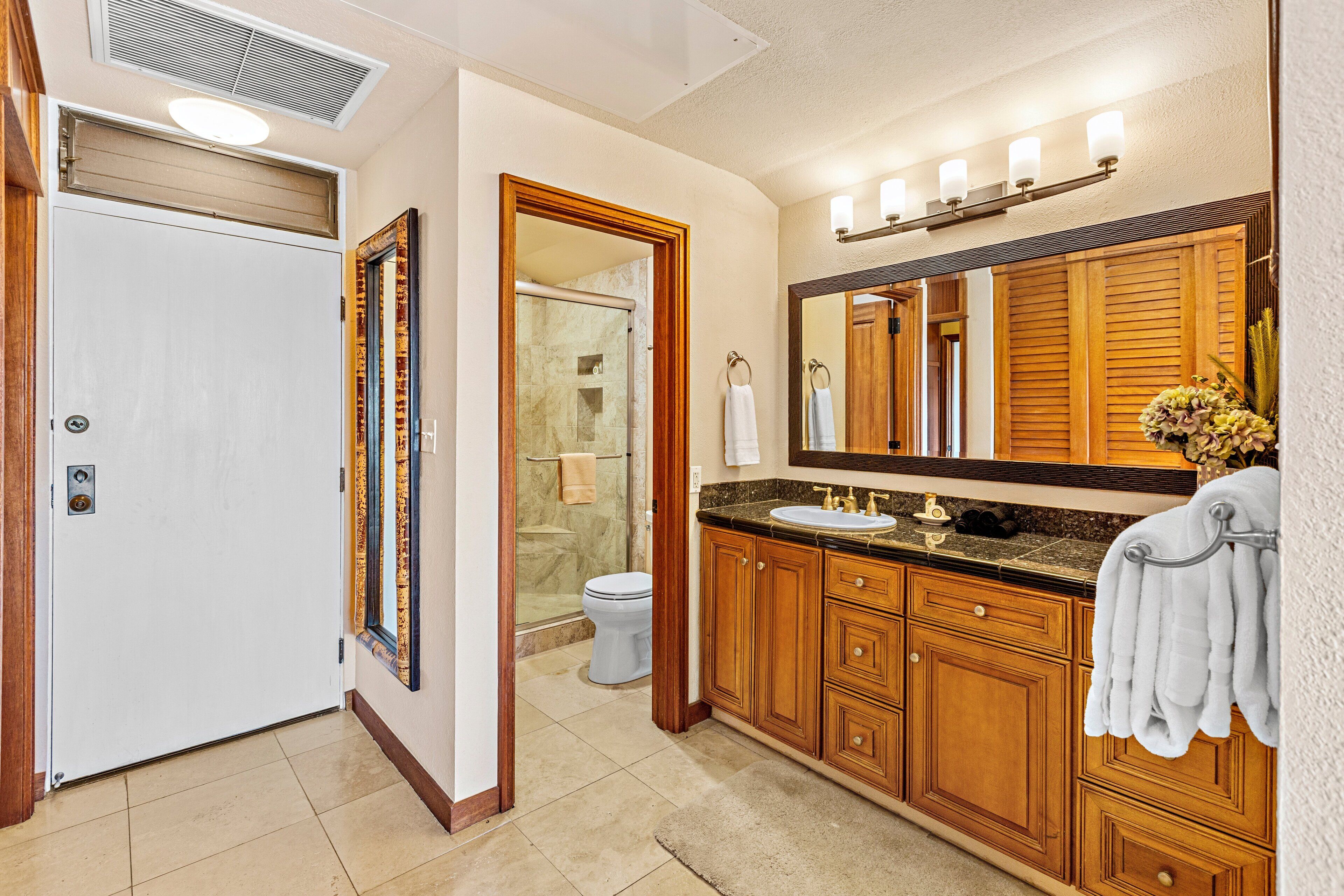 Une salle de bain avec des meubles en bois, un lavabo, un miroir et un espace douche.