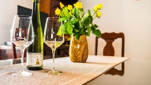 A table with a bottle of Zlatan Vino and two wine glasses, a yellow flower vase, and a wooden chair. - Picturesque House in Kaštela Old Town Near Beach and Local Amenities (Kastela)