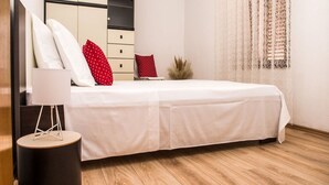 A bedroom with a bed, a bedside table, a lamp, a wardrobe, and a decorative wall panel. - Picturesque House in Kaštela Old Town Near Beach and Local Amenities (Kastela)