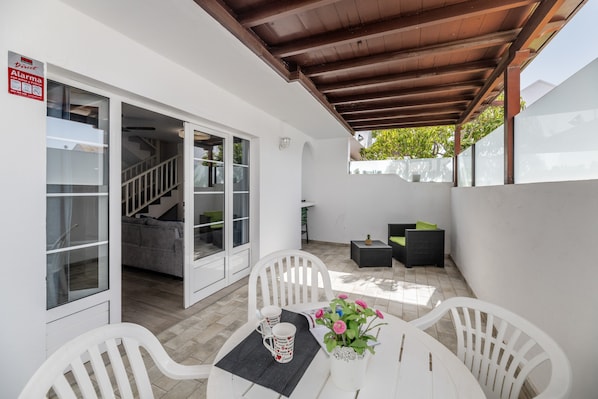 Un patio con una mesa, sillas y una planta en maceta.