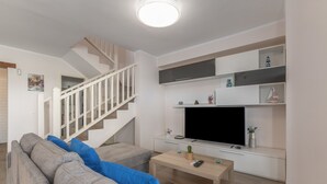 Een moderne woonkamer met een trap, een flatscreen televisie, een salontafel en een bank.