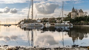 Puerto deportivo con barcos, un castillo y cielo despejado.
