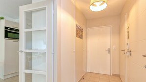 Un pasillo con una puerta blanca, una lámpara encendida y una zona de cocina con horno.
