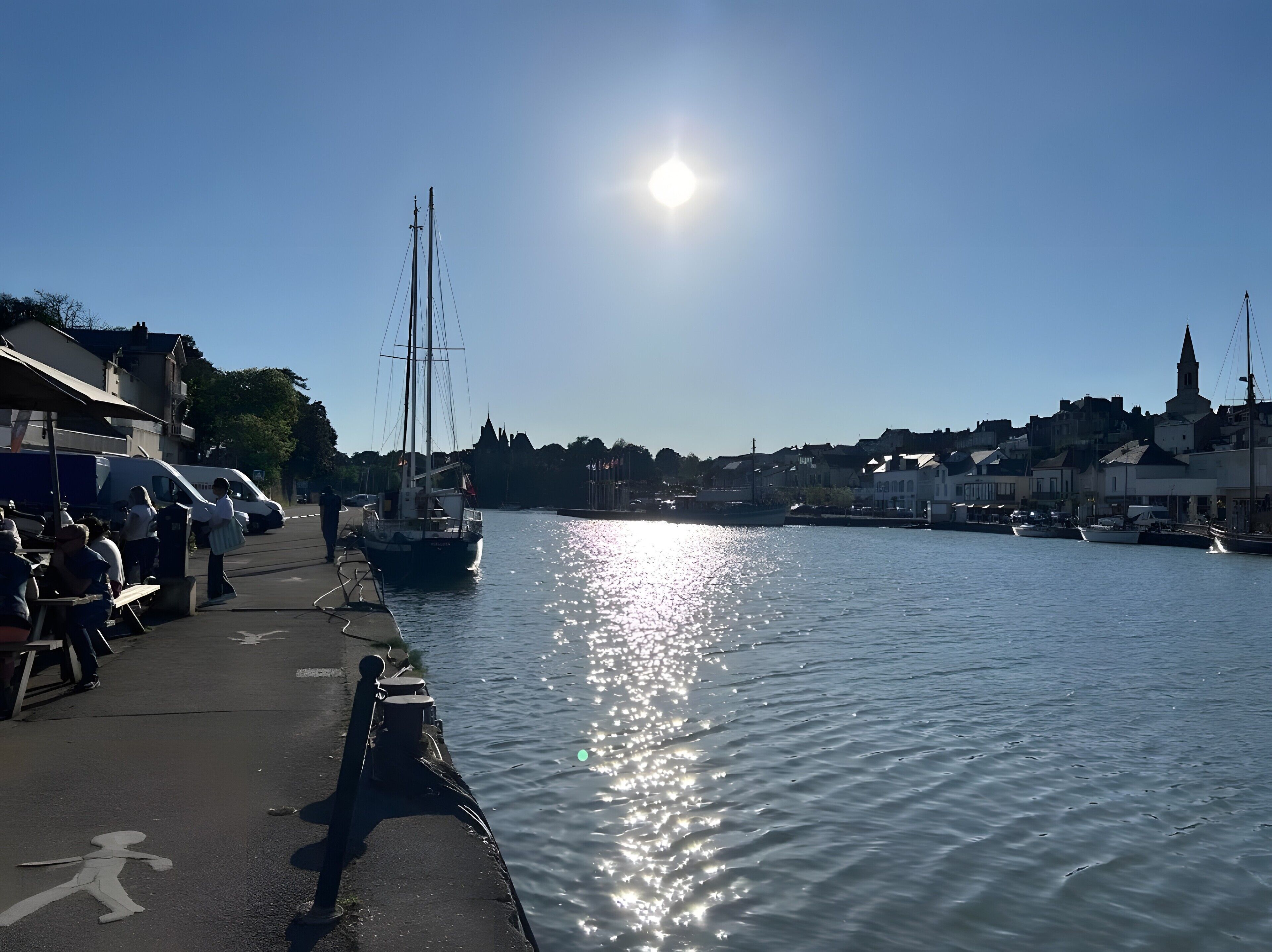 Un port avec des bateaux, un ciel dégagé et des bâtiments le long de la rive.