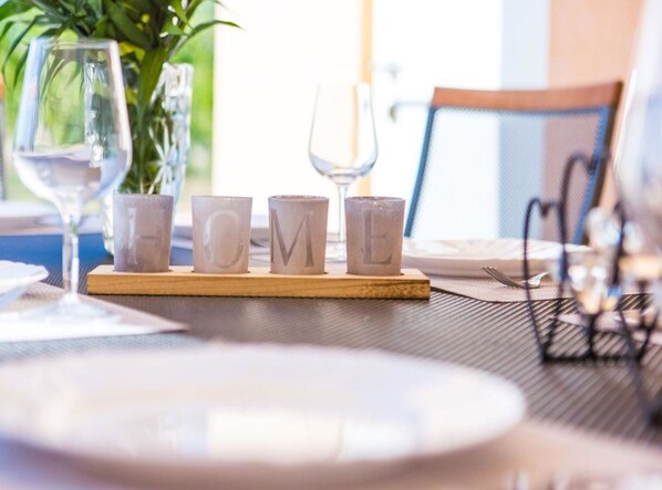 A table set with a glass, a plate, and four cups with letters spelling "HOME" on a coaster. - Kastel Luksic Scenic Villa With Pool (Kastela)