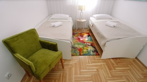A room with two beds, a green armchair, and a colorful rug. - Trogir Stylish Apartment With Balcony and Sea View (Trogir)