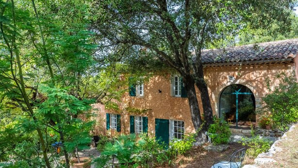 A rustic building with a tiled roof, a glass door, and a small patio area with a chair. - Charming House in Lorgues with Terrace and Private Garden (Lorgues)