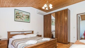 Une chambre à coucher avec un lit en bois, une table de chevet, une commode, un miroir et une armoire.