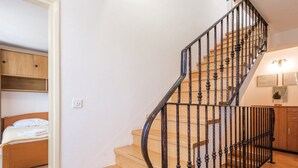 Un escalier avec des marches en bois et des rampes en métal noir, menant à une chambre à coucher avec un lit et une tête de lit en bois.