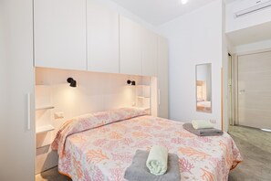 A bedroom with a bed, bedside tables, a mirror, and a wardrobe.