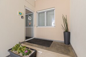 L’entrée d’un hôtel, avec une porte en verre, une plante en pot et une fenêtre.