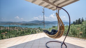 A hanging chair on a balcony with a view of a lake and mountains. - Villa 'Melikokia' with Sea View, Wi-Fi and Air Conditioning (Unknown)
