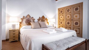 Een netjes opgemaakt bed met een hoofdeinde, nachtkastjes met lampen en een groot decoratief paneel aan de muur.