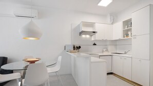 A modern kitchen with white cabinetry, a central island, and a hanging pendant light. - Oasis 38: Pool, Private Parking, Steps from the Beach (Lido di Jesolo)