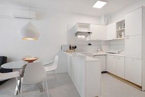 Una cocina moderna con armarios blancos, una isla central y una lámpara colgante.