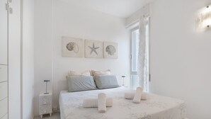 A bedroom with a bed, pillows, a bedside table, and wall art. - Oasis 38: Pool, Private Parking, Steps from the Beach (Lido di Jesolo)