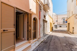 A narrow street with closed shops and a building with an open door.