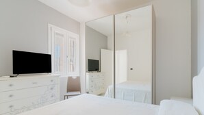 A bedroom with a bed, a dresser, a television, and a mirror. - Holiday Home 'Casa 406' with Balcony and Air Conditioning (Torre San Giovanni)