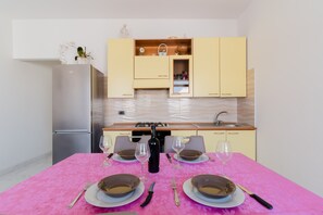Une cuisine compacte comprenant une table à manger pour quatre personnes, un réfrigérateur et un évier.