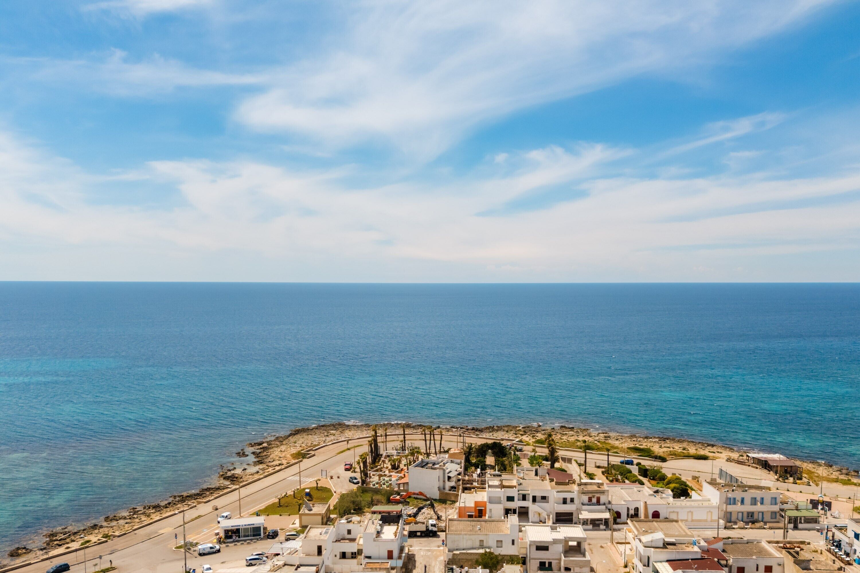 Un pueblo costero con edificios, una carretera y el mar.