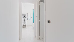 A hallway with a white door, a radiator, and a metal rack. - Holiday Home 'Casa 406' with Balcony and Air Conditioning (Torre San Giovanni)