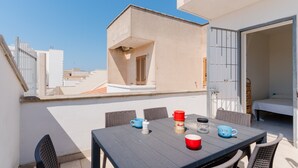 A rooftop terrace with a table set for two, a small window, and a door leading to a bedroom. - Holiday Home 'Casa 406' with Balcony and Air Conditioning (Torre San Giovanni)