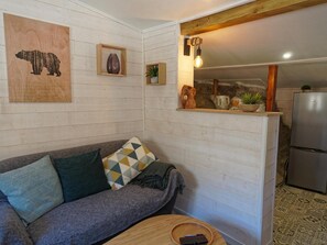 Un salon confortable avec un canapé, une table en bois et un coin cuisine équipé d’un réfrigérateur.