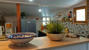 Eine Küche mit einer Holzausziehtheke, einer blau-weißen Schüssel, einem Blumentopf und einem Kühlschrank.