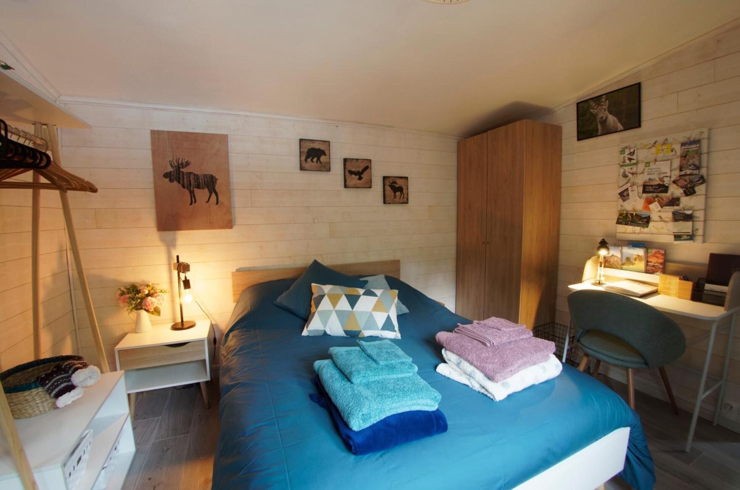 Un dormitorio con cama, almohadas, un escritorio y una silla.