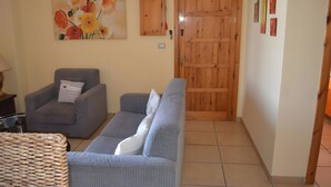 Una sala de estar con sofá, sillón y puerta de madera.