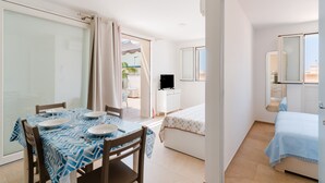 Une pièce comprenant un lit, un bureau, une chaise, une table avec des assiettes et des verres, et un téléviseur.