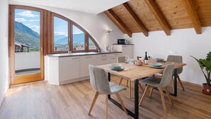 Eine moderne Küche mit großem Fenster, Holzbalkendecke und Essbereich mit Tisch für vier Personen.