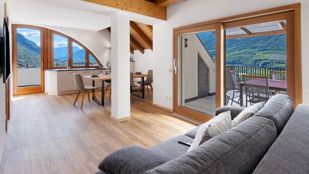 Ein modernes Interieur mit Holzboden, einem Essbereich, einer Couch und Bergblick durch große Fenster.