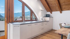 Eine Küche mit einem großen Fenster, Holzbalken an der Decke und Bergblick.