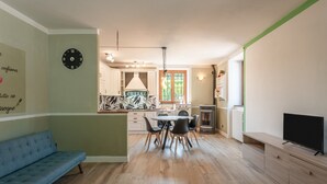 A modern kitchen with a dining area, a sofa, and a TV.