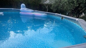 A swimming pool with clear blue water, surrounded by a tiled deck.