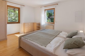 A bedroom with a bed, two windows, a radiator, and a wardrobe. - Apartment 'Vinlauris 46' with Mountain View, Private Outdoor Area and Wi-Fi (Tschars)