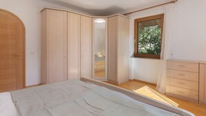 A bedroom with a bed, a wardrobe, a mirror, a window, and a dresser. - Apartment 'Vinlauris 46' with Mountain View, Private Outdoor Area and Wi-Fi (Tschars)