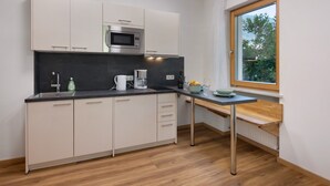 A modern kitchen with a built-in microwave, a coffee maker, and a window with a view of greenery. - Apartment 'Vinlauris 46' with Mountain View, Private Outdoor Area and Wi-Fi (Tschars)