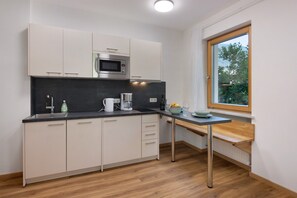 A modern kitchen with a built-in microwave, a coffee maker, and a window with a view of greenery. - Apartment 'Vinlauris 46' with Mountain View, Private Outdoor Area and Wi-Fi (Tschars)