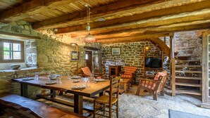 Un coin repas rustique avec des murs en pierre, des poutres en bois et un escalier en pierre.