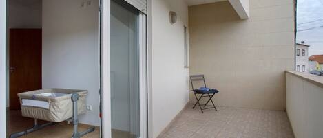 A balcony with a baby changing station, a chair, and a view of the street.