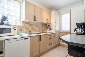 Una cocina con armarios de madera, lavavajillas, microondas y cafetera.