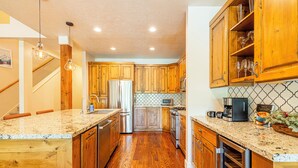 A kitchen with wooden cabinets, granite countertops, stainless steel appliances, and a wine cooler. - Charming Mountain Escape Near All the Action (Park City)