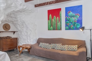 A room with a brown sofa, a wooden side table, a small stool, and two paintings on the wall. - 'Casa Cueva' with Mountain View, Private Terrace and Private Garden (Juncalillo)