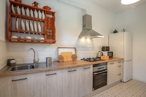 Una cocina moderna con encimera de madera, pileta de acero inoxidable y muebles de cocina blancos.