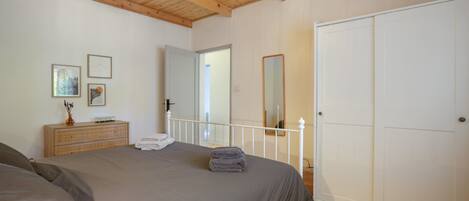 A bedroom with a bed, a dresser, a mirror, and a wardrobe.