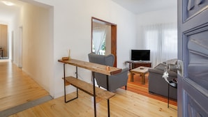 A modern living room with a wooden bench, grey sofa, and a television. - Holiday Home 'Picarus' with Private Terrace, Wi-Fi, Air Conditioning & Heating (tacoronte)